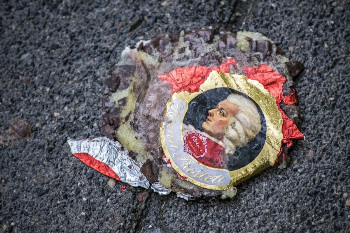 Crushed Mozart chocolate wrapper melting into wet asphalt